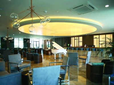 Lobby di hotel moderna con soffitto circolare e pianoforte bianco a coda al centro.