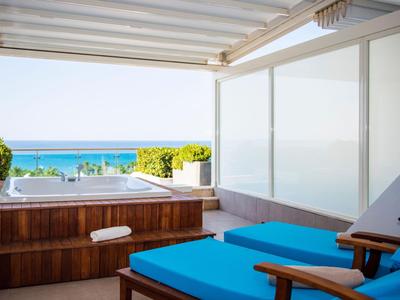 Terrazza moderna con vasca idromassaggio e lettini blu con vista sul mare.