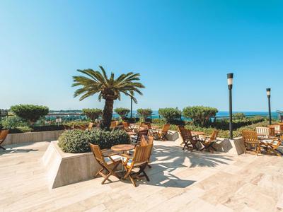 Terrasse avec tables et chaises face à la mer sous un ciel dégagé.