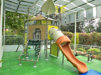 Area giochi colorata per bambini con scivolo sotto un tetto trasparente all'aperto.