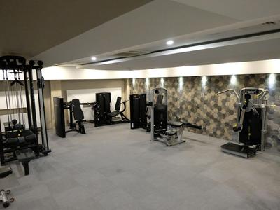 Salle de sport bien éclairée avec équipements modernes et sol moquetté beige.