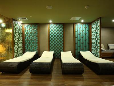 Quatre chaises longues modernes avec serviettes blanches dans un espace spa calme avec éclairage tamisé.