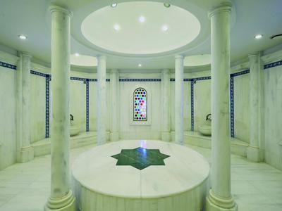 Stanza rotonda luminosa in marmo con colonne e vetrate colorate.