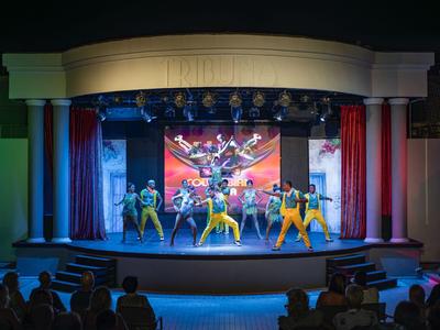 Spettacolo sul palco con persone che ballano davanti a un grande schermo in un teatro dell'hotel.