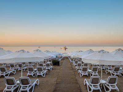 Spiaggia vuota con ombrelloni bianchi e sdraio all'alba.