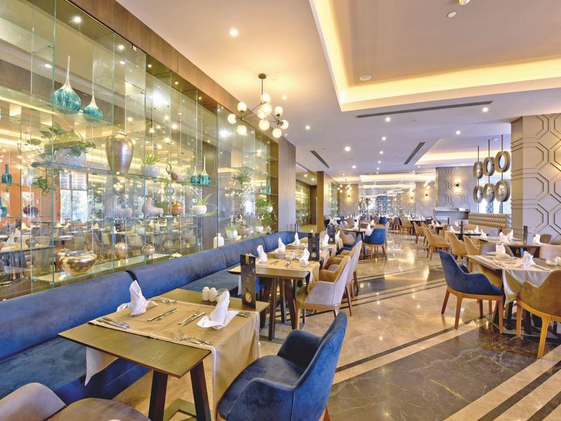 Zona pranzo moderna dell'hotel con sedie blu, tavoli in legno e illuminazione elegante.