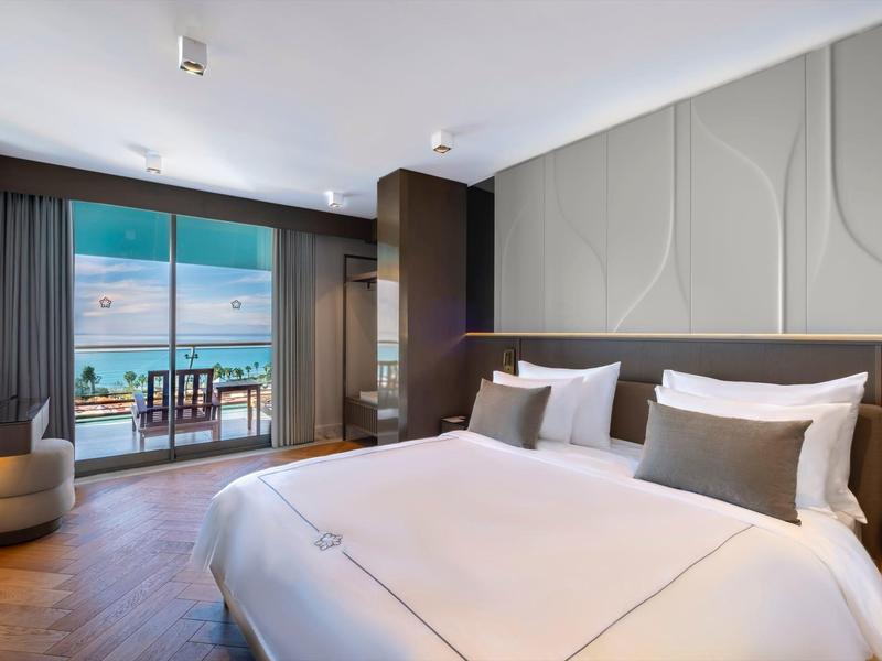 Camera d'hotel moderna con letto grande e balcone con vista sul mare.
