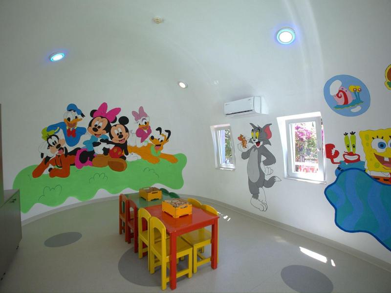 Stanza per bambini con sedie colorate e murales di personaggi dei cartoni animati.