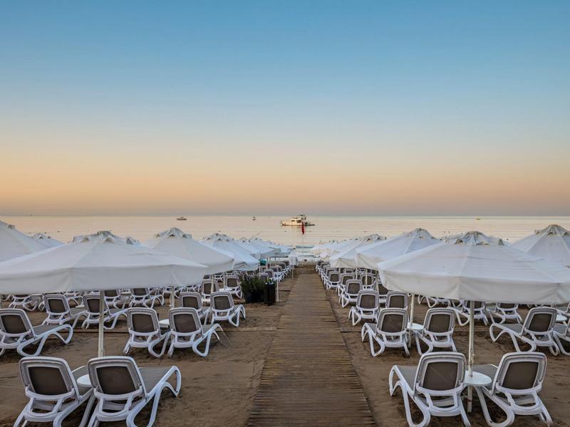Spiaggia vuota con ombrelloni bianchi e sdraio all'alba.