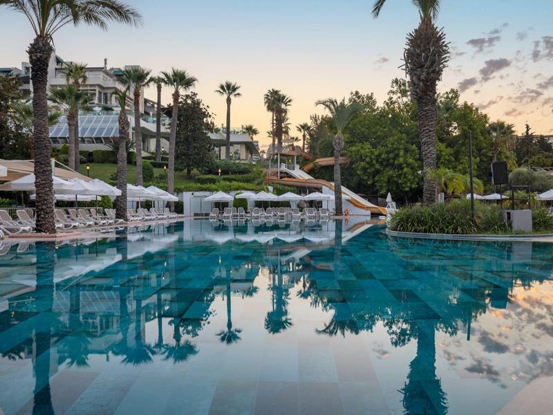 Elegante piscina all'aperto con lettini e palme in un hotel al tramonto
