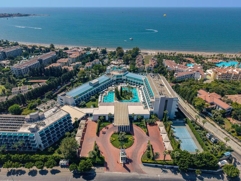 Vista aerea di un grande resort con più edifici, piscine e accesso diretto alla spiaggia.