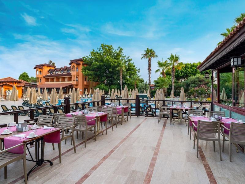 Ristorante all'aperto con molti tavoli e sedie su una terrazza con sole