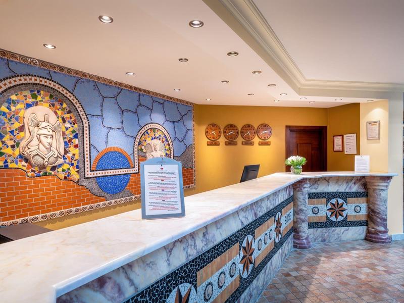 Area reception dell'hotel luminosa con piastrelle a mosaico e arte murale decorativa.