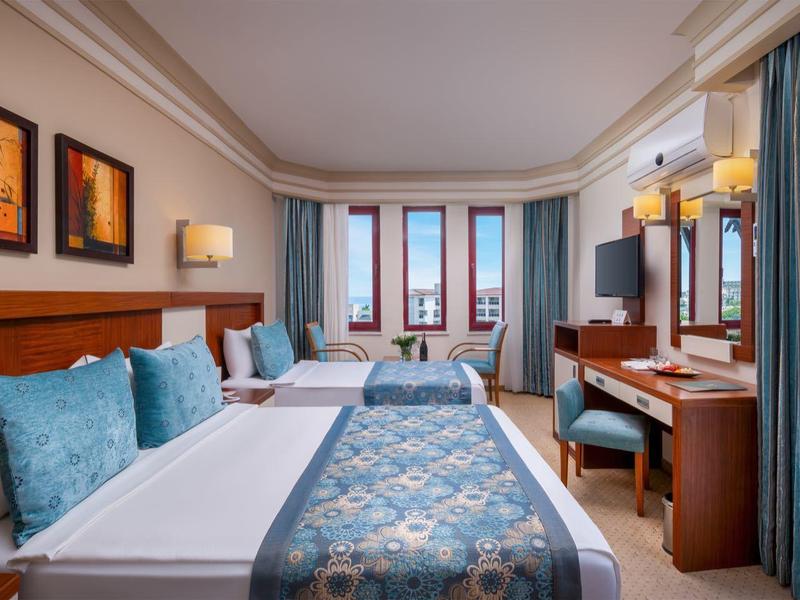 Elegante camera d'hotel con letto matrimoniale, TV, scrivania e finestra con vista mare.