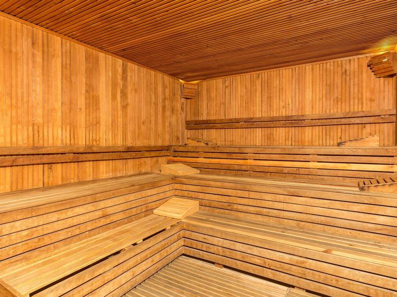 Sauna in legno chiaro con panche a più livelli e pareti rivestite in legno.