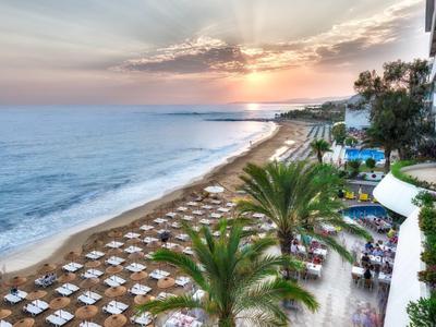 Hôtel de plage avec coucher de soleil, chaises longues et palmiers au bord de la mer