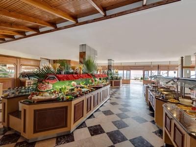 Grande zone de buffet dans un restaurant avec plafond en bois naturel et grandes fenêtres.