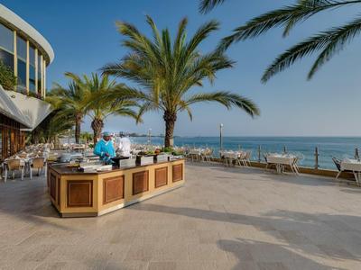 Restaurant en plein air avec des palmiers et vue sur la mer par ciel clair