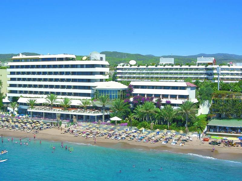 Grand hôtel avec transats sur plage de sable et eau bleue claire