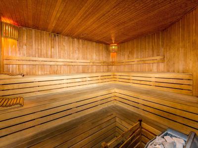 Holzsauna mit mehrstufigen Bänken, Holzwänden und Saunaofen mit heißen Steinen.