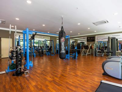 Gimnasio espacioso con suelo de madera, diversas máquinas de ejercicio y un saco de boxeo.