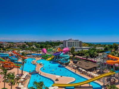 Gran parque acuático con toboganes coloridos y varias piscinas bajo un cielo azul claro.
