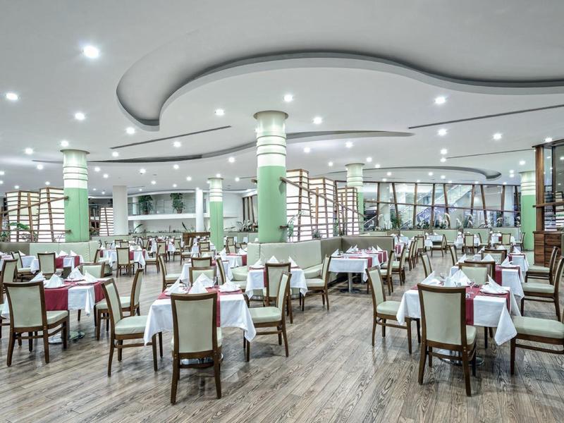 Large modern dining hall with white tables, wooden floor, and many chairs.