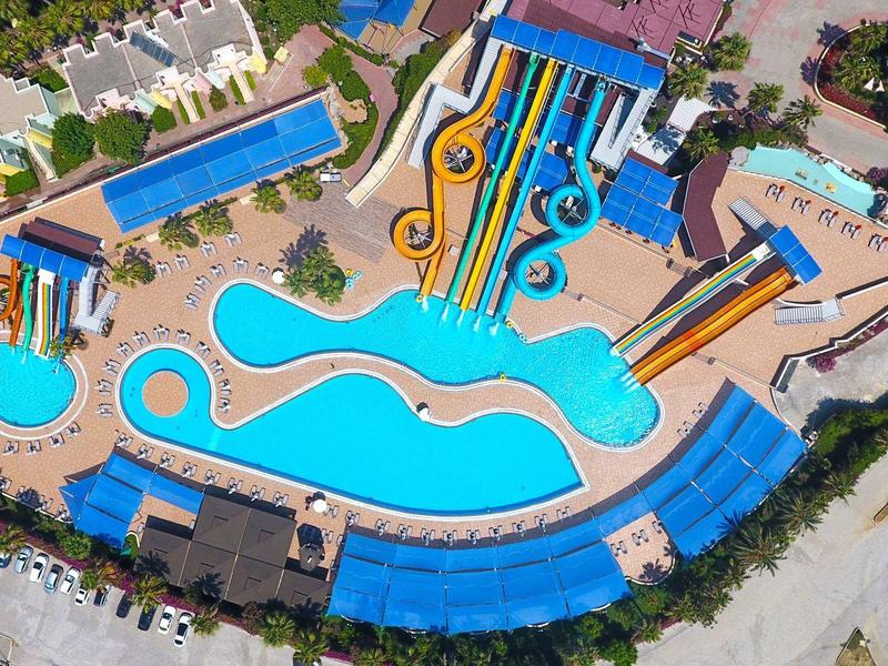 View of a water park with multiple water slides and a large blue pool.