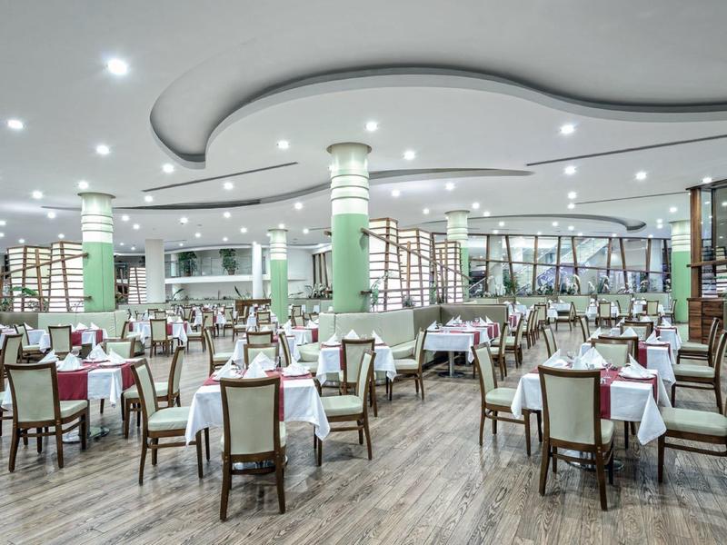 Large modern dining room with many set tables and bright ceiling lights.