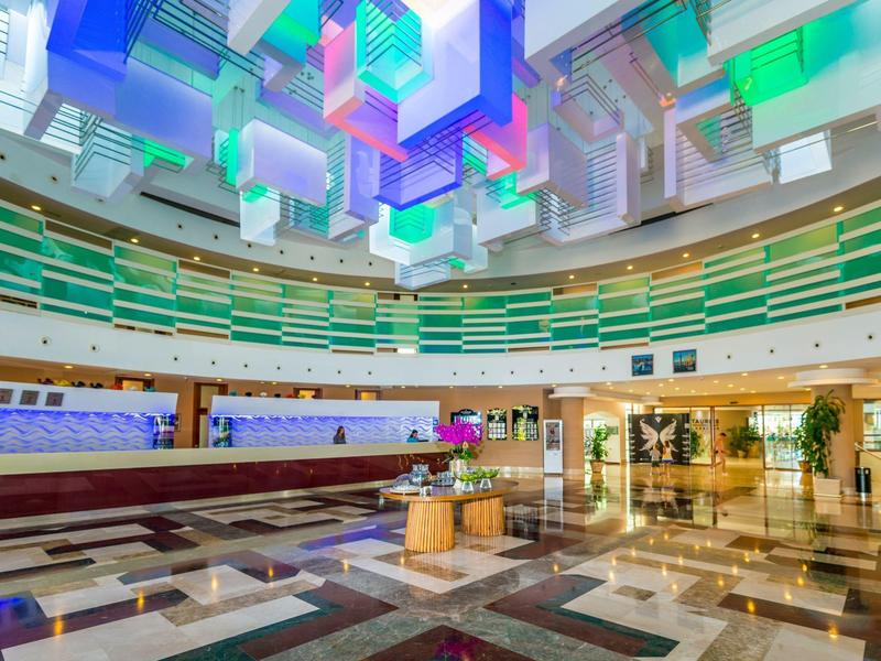 Large hotel lobby area with colorful hanging light installations and marble flooring.