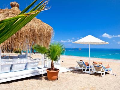 Relaksująca plaża z parasolem, leżakami i chatką z trzciny pod błękitnym niebem.