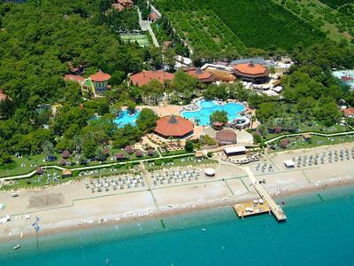 Hotelcomplex met zwembad, strand en groene bomen aan de kust.