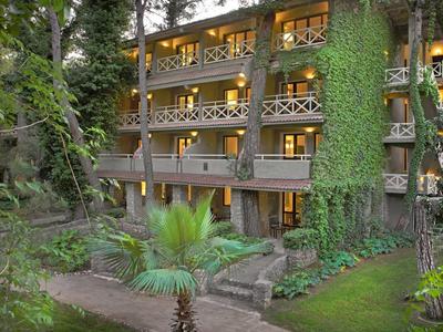 Meerdere verdiepingen tellend hotelgebouw met balkons, omgeven door weelderig groen bij schemering.