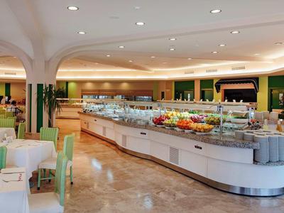 Grote, lichte buffetruimte met veel fruit en zitplaatsen in een restaurant.