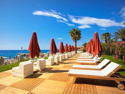 Rij van ligstoelen met rode parasols op houten terras aan zee