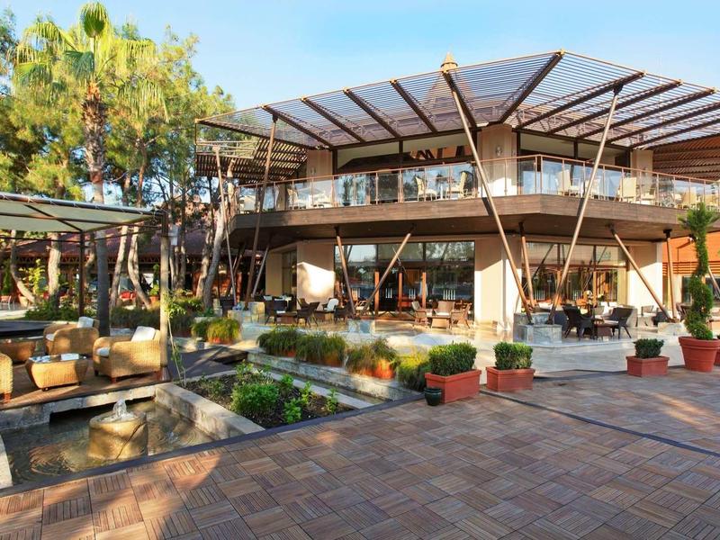 Modern hotelgebouw met grote glazen ramen en een gezellige zithoek buiten.