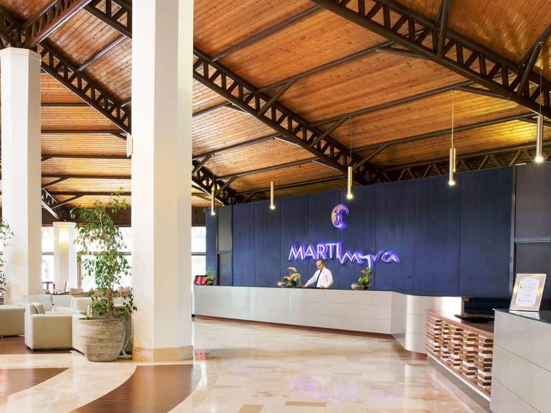 Moderne hotel lobby met houten plafond, grote receptiebalie en warme verlichting.