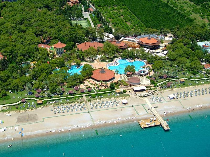 Hotelcomplex met zwembad, strand en groene bomen aan de kust.