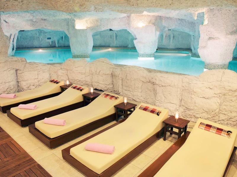 Ontspanningsruimte met ligstoelen en uitzicht op een verlicht zwembad in de spa.