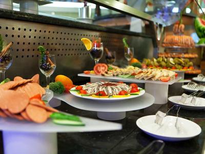 Buffet mit verschiedenen kalten Vorspeisen, dekoriert mit Zitrusfrüchten und Gläsern im Hintergrund.
