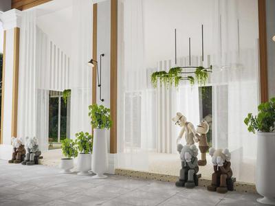 Moderne weiße Fassade mit Skulpturen in Tierform und grünen Pflanzen in Töpfen.