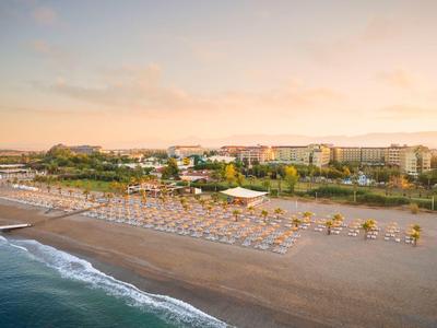 Ampia spiaggia sabbiosa con ombrelloni e hotel sullo sfondo al tramonto.