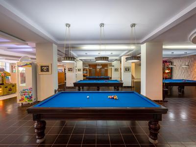 Vista interna di una sala da biliardo con più tavoli da biliardo e illuminazione moderna.