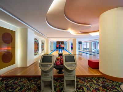 Pista da bowling moderna con due corsie, due schermi e opere d'arte alle pareti in un hotel.