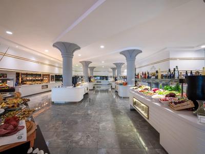 Ristorante a buffet moderno con colonne, ampio spazio per sedersi e cibo vario su lunghe banconi.