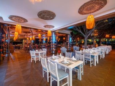 Ristorante accogliente e elegante con tavoli e sedie bianchi, illuminazione calda e atmosfera aperta.