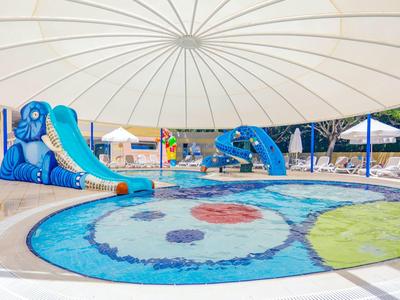 Area giochi per bambini con piscina colorata e scivoli d'acqua blu sotto un ombrellone bianco.