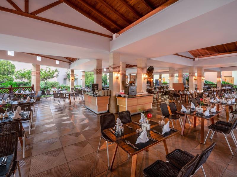 Grande ristorante aperto con tavoli apparecchiati e tetto in legno.