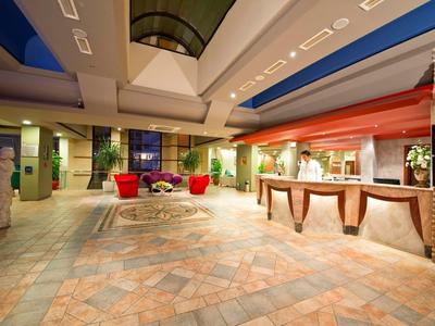 Atrio dell'hotel con reception, area salotto e illuminazione calda.