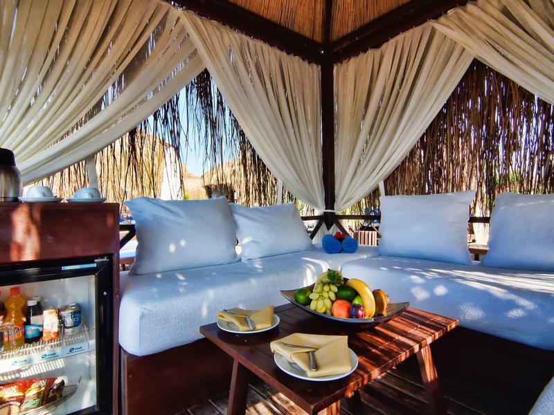 Salotto confortevole con divano blu e minibar sotto un tetto in legno, atmosfera esotica.